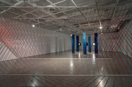 Modern art display with blue pillars and red wires.