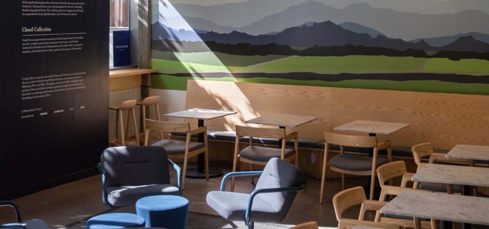 Inside a coffee shop with lots of seating and a wall mural of mountains.