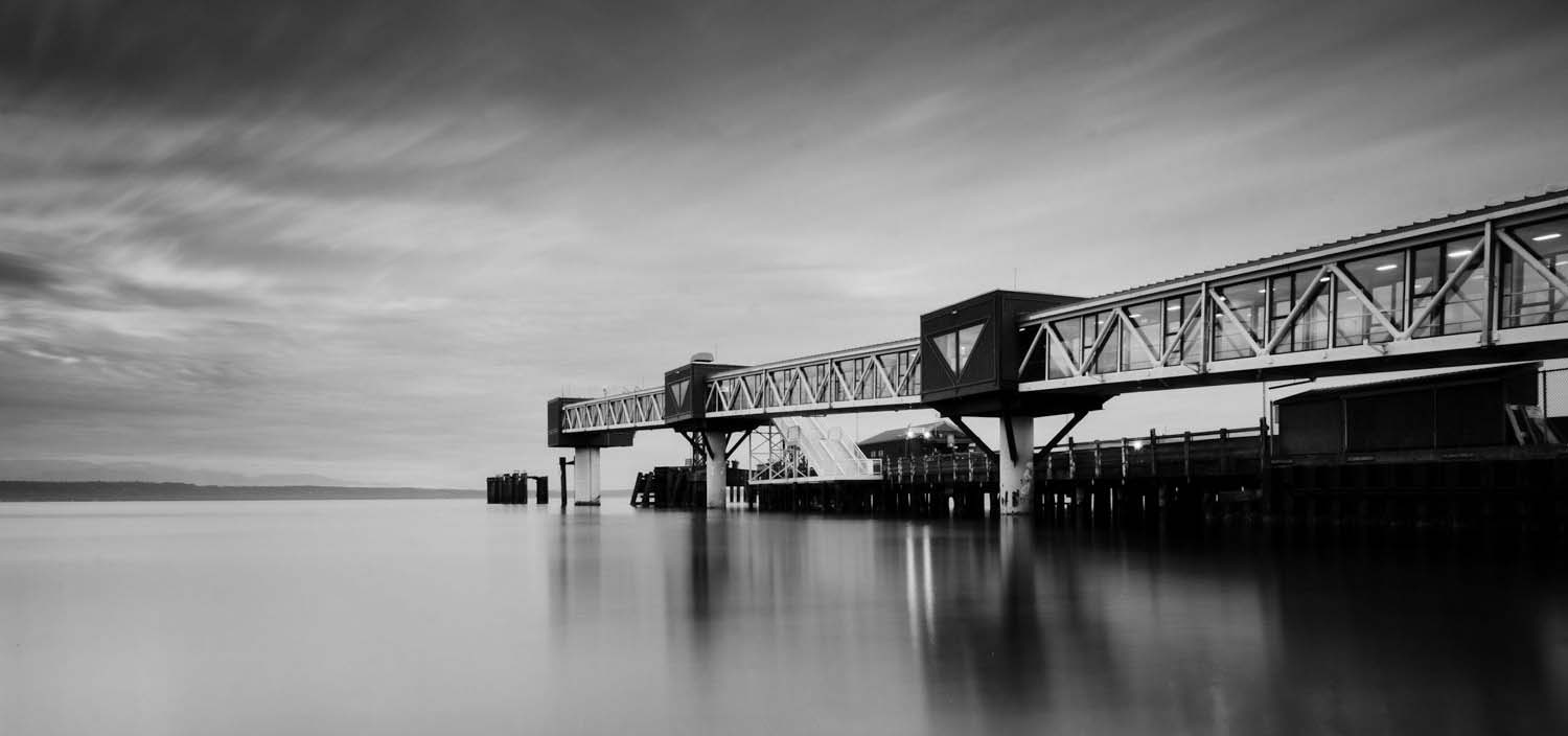 Black and white photo of an elevated tunnel over a body of water.