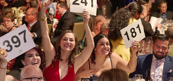 People holding up bidding numbers at an auction.