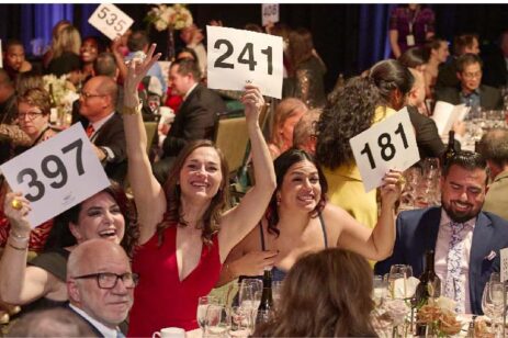 People holding up bidding numbers at an auction.