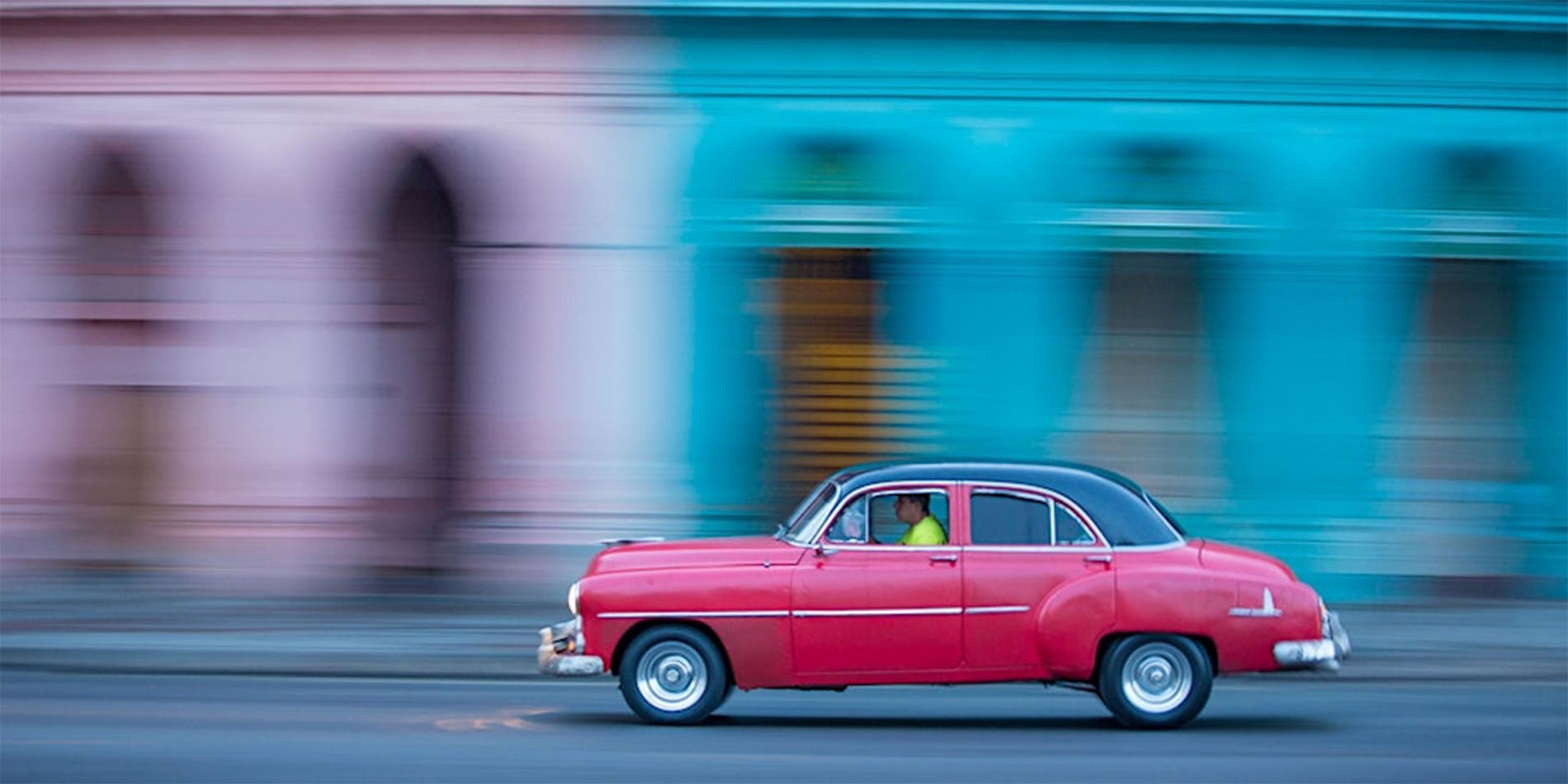 car in motion in front of colorful buildings