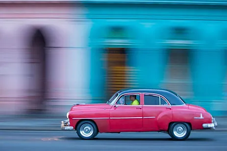 car in motion in front of colorful buildings