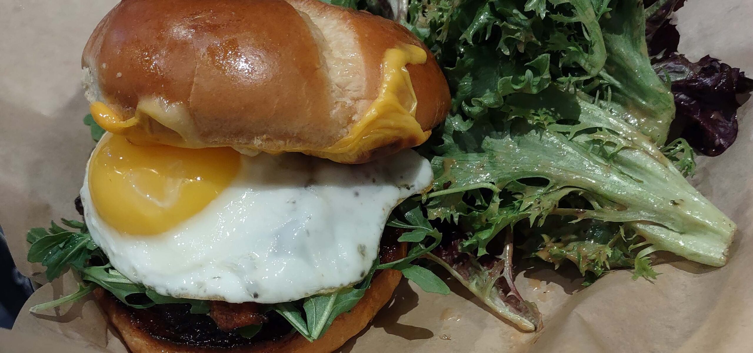 Egg breakfast sandwich with a side salad.