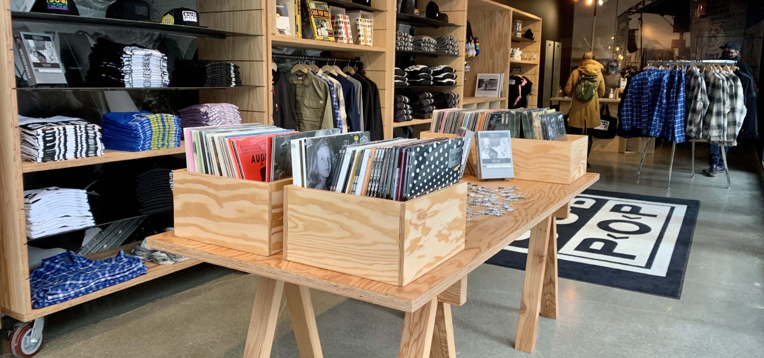 Inside of a record store filled with record stands and clothing racks.