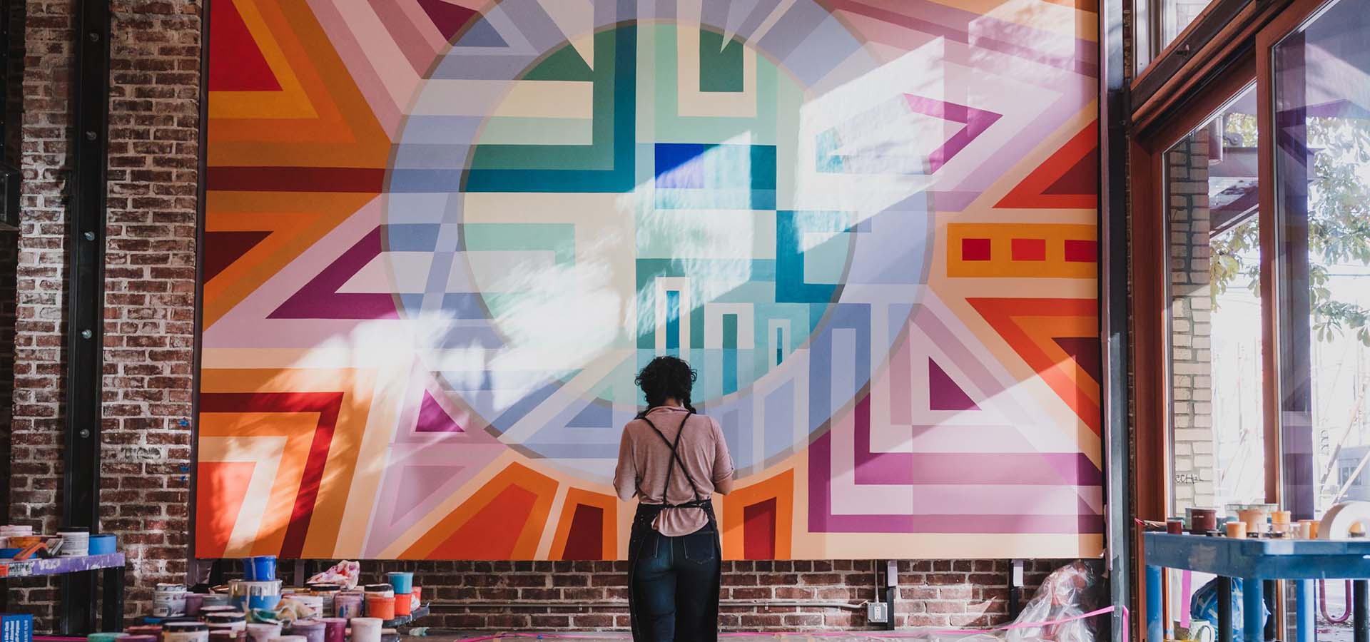 Artist Marela Zacarías working on a painting with vibrant colors.