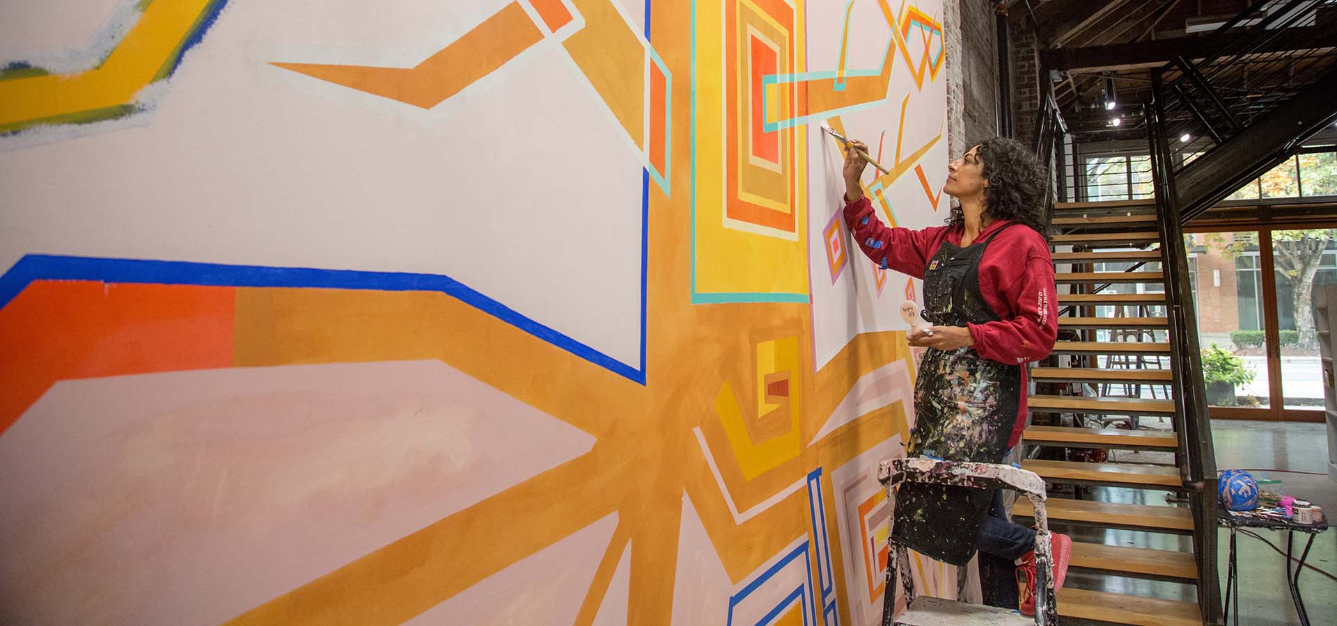 Artist Marela Zacarías working on a painting with vibrant colors.