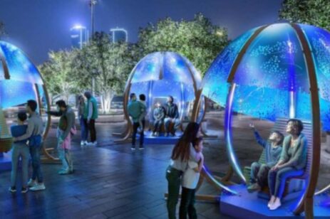 People sitting is domed seats on a plaza.