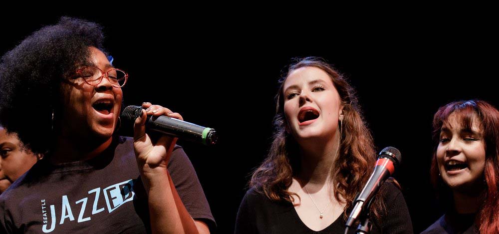 Three girls singing on stage.