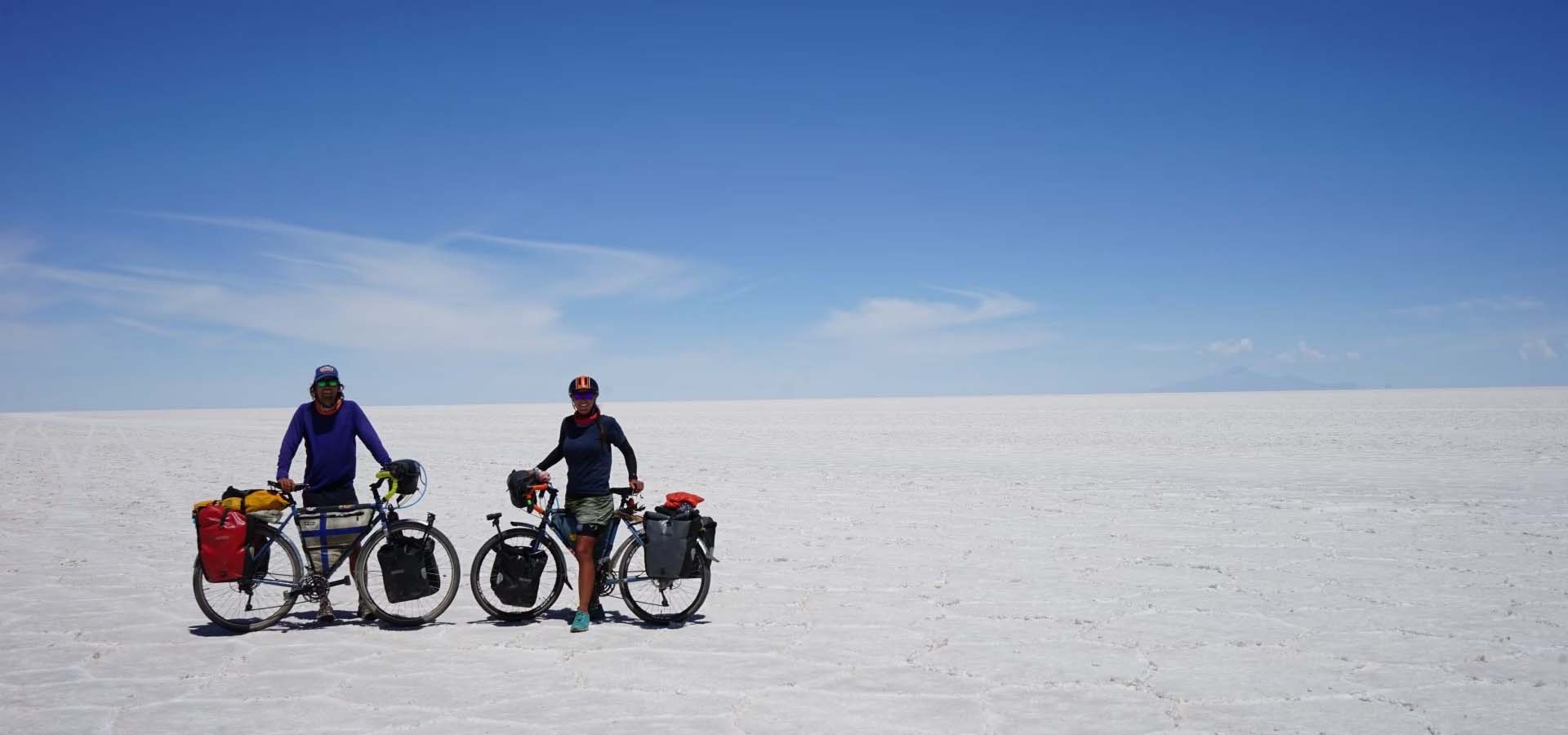 Two people riding bikes through a desert.
