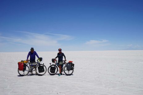Two people riding bikes through a desert.