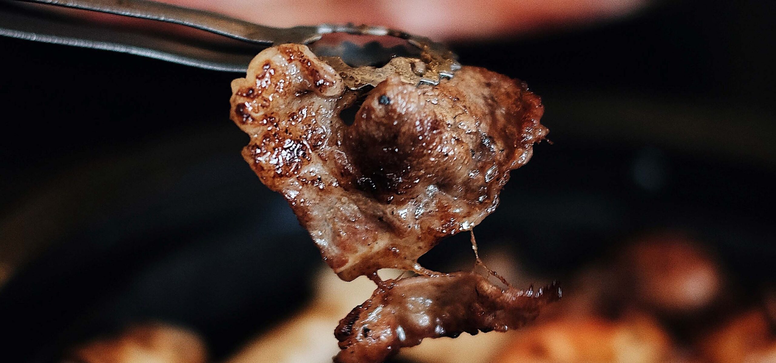 Close up of a grilled piece of Korean BBQ meat on a fork.