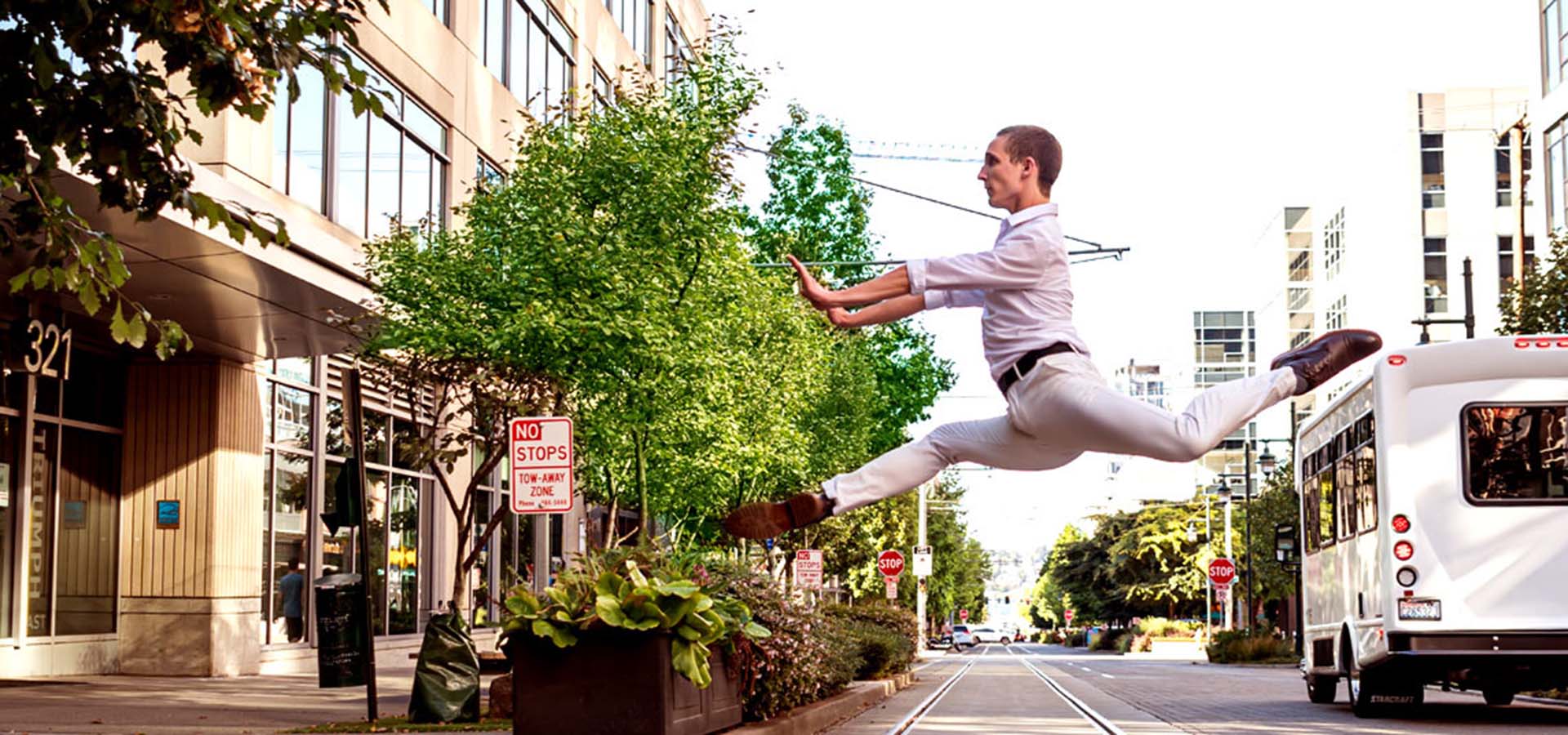 Male dancer leaping over streetcar tracks.