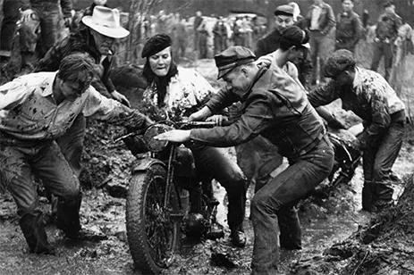 historical image of people pulling motorcycle through mud