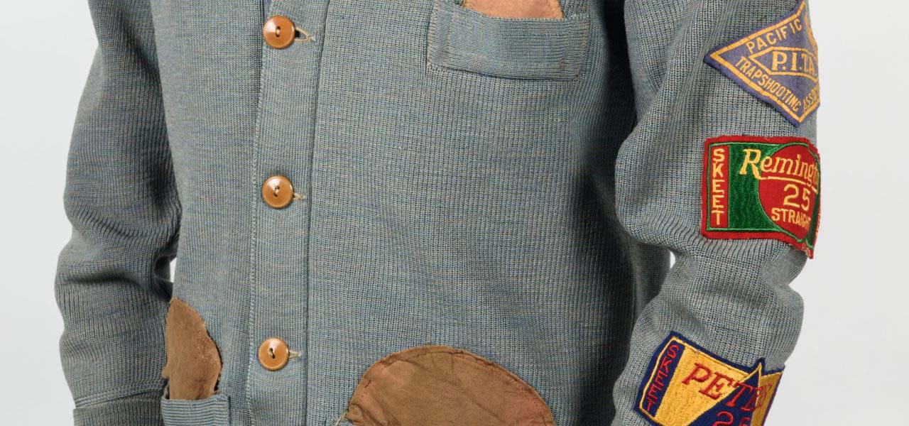 A gray knit button-up sweater with some patches on it.