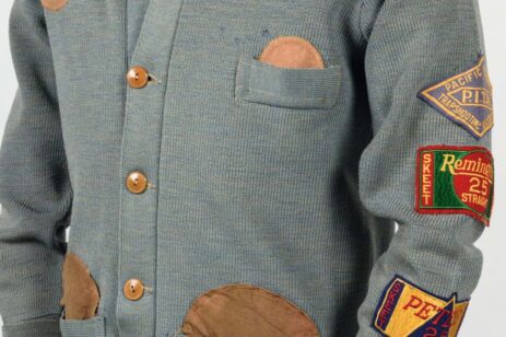 A gray knit button-up sweater with some patches on it.