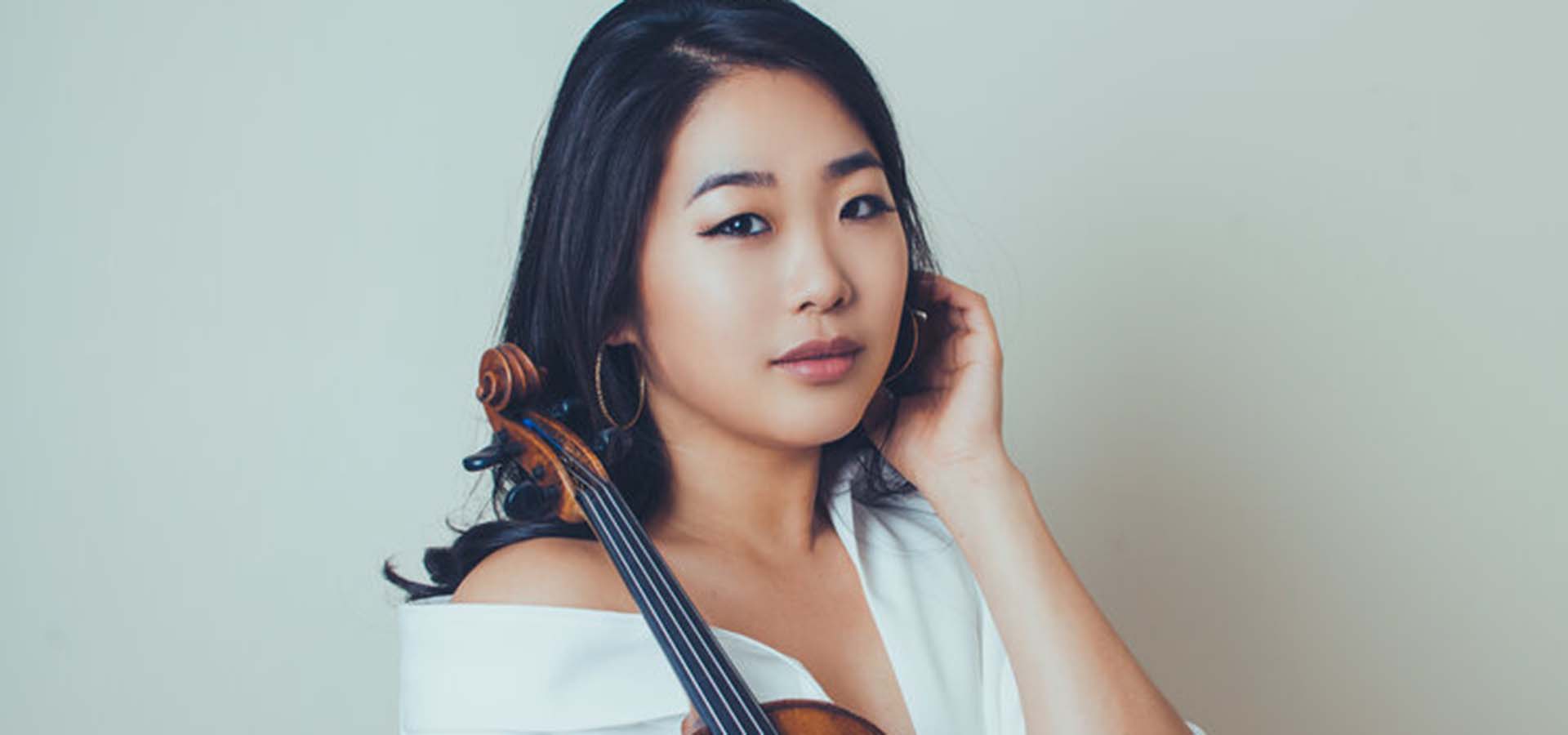 Asian women dressed in white holding a violin