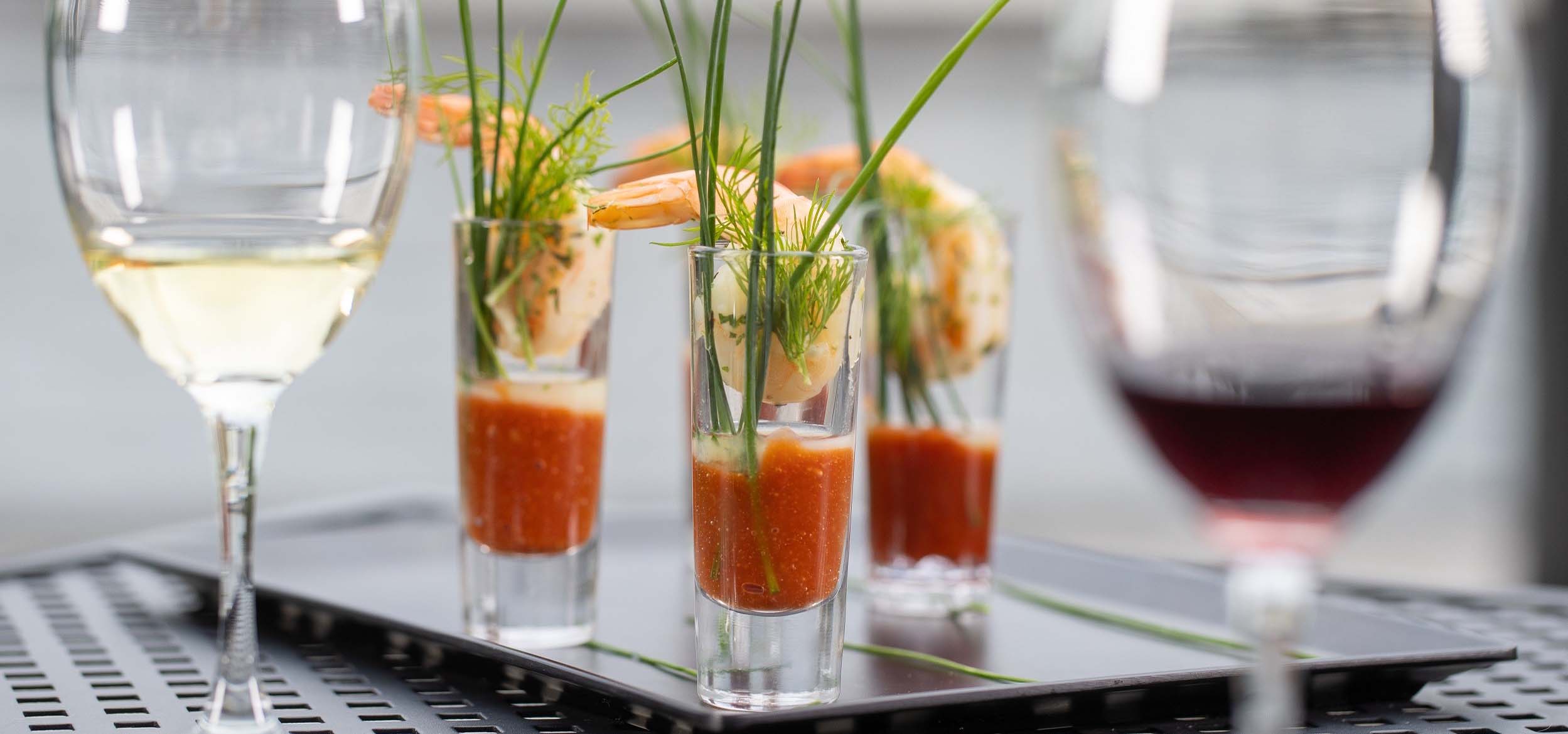 Tall shot glasses filled with cocktail sauce and prawns.