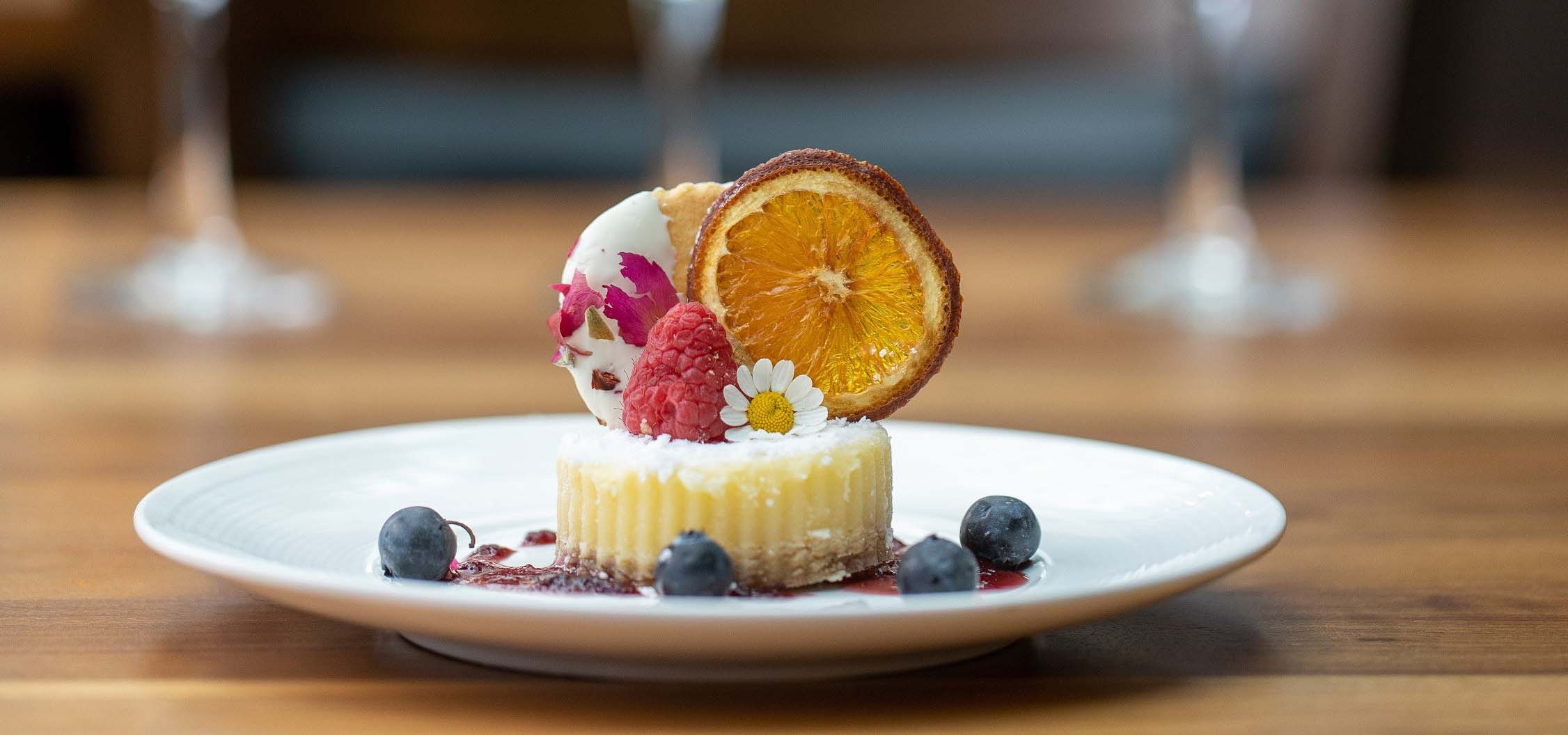 Fancy lemon tart topped with candied orange and berries.