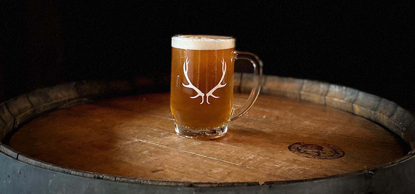 Stein of beer on top of a wood barrel.