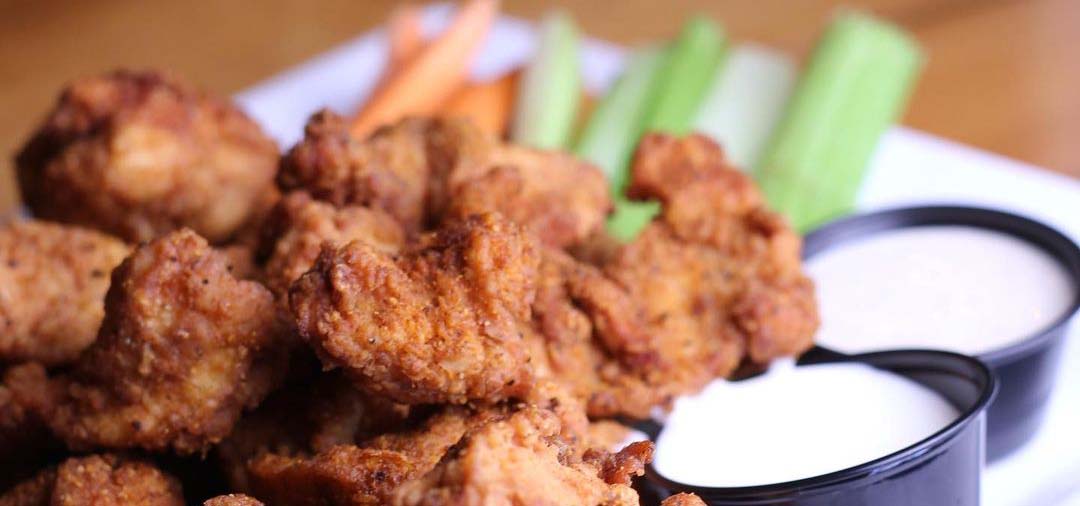 White plate of buffalo wings, celery and ranch dipping sauce.