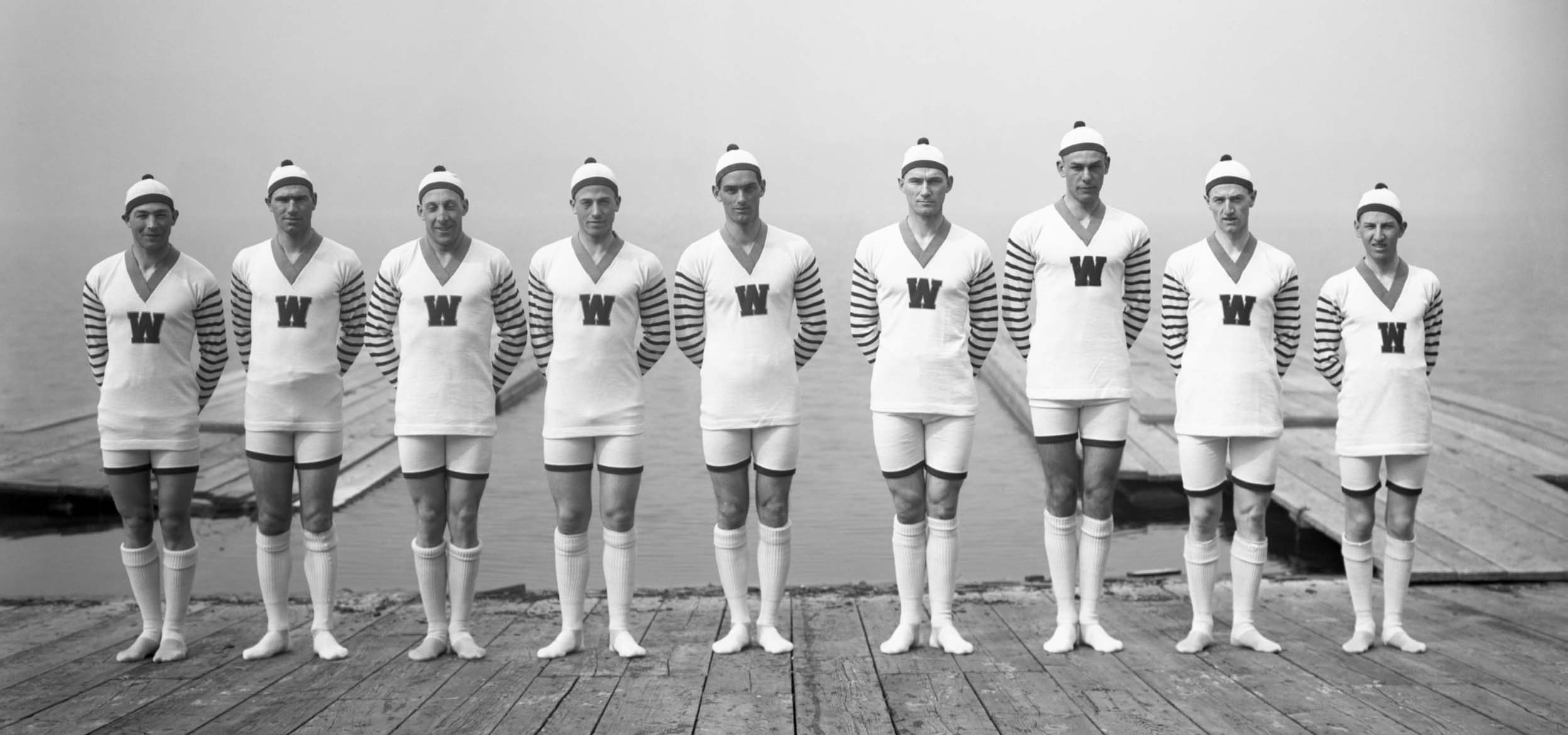 Old photo of a rowing team on a pier.