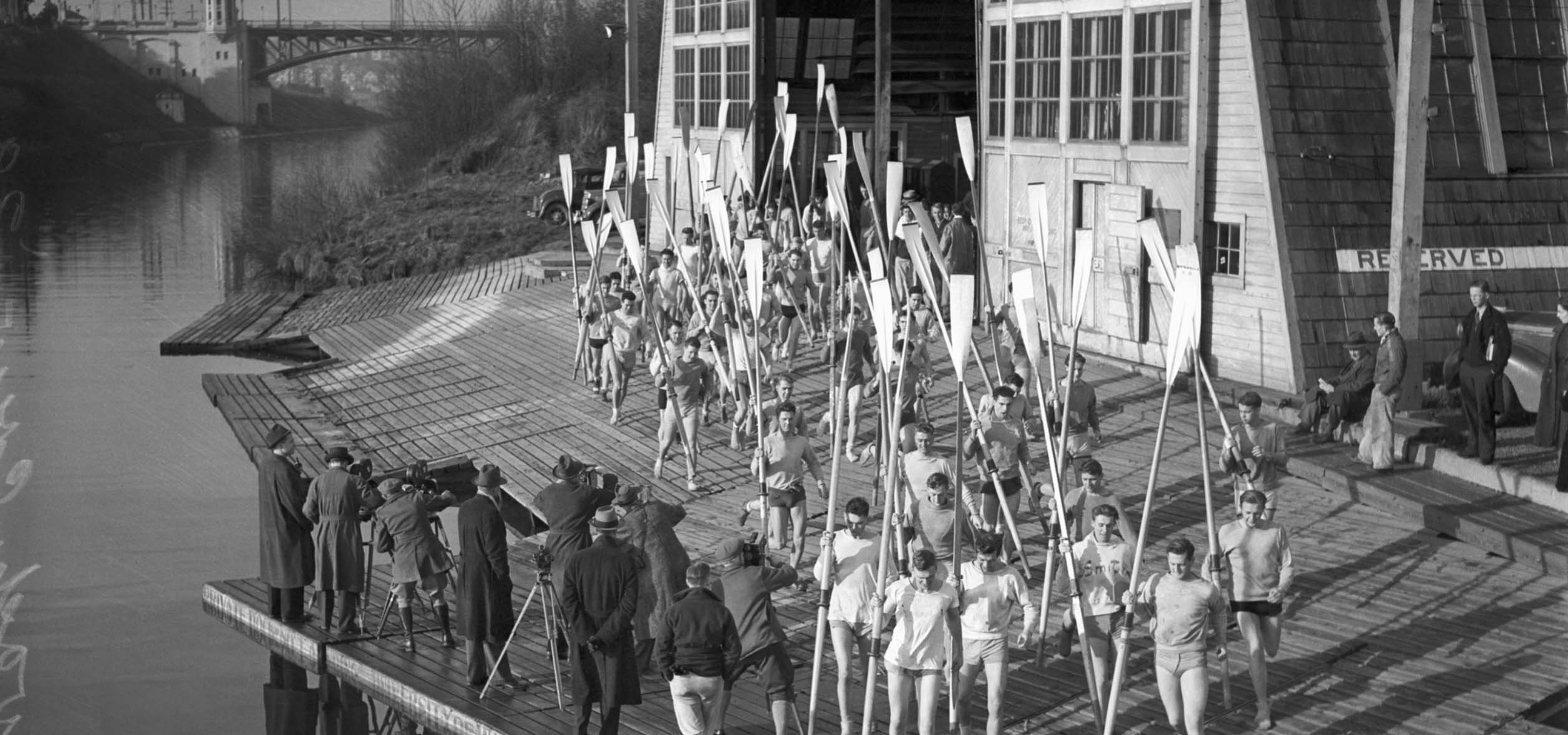 Old photo of a rowing team on a pier.