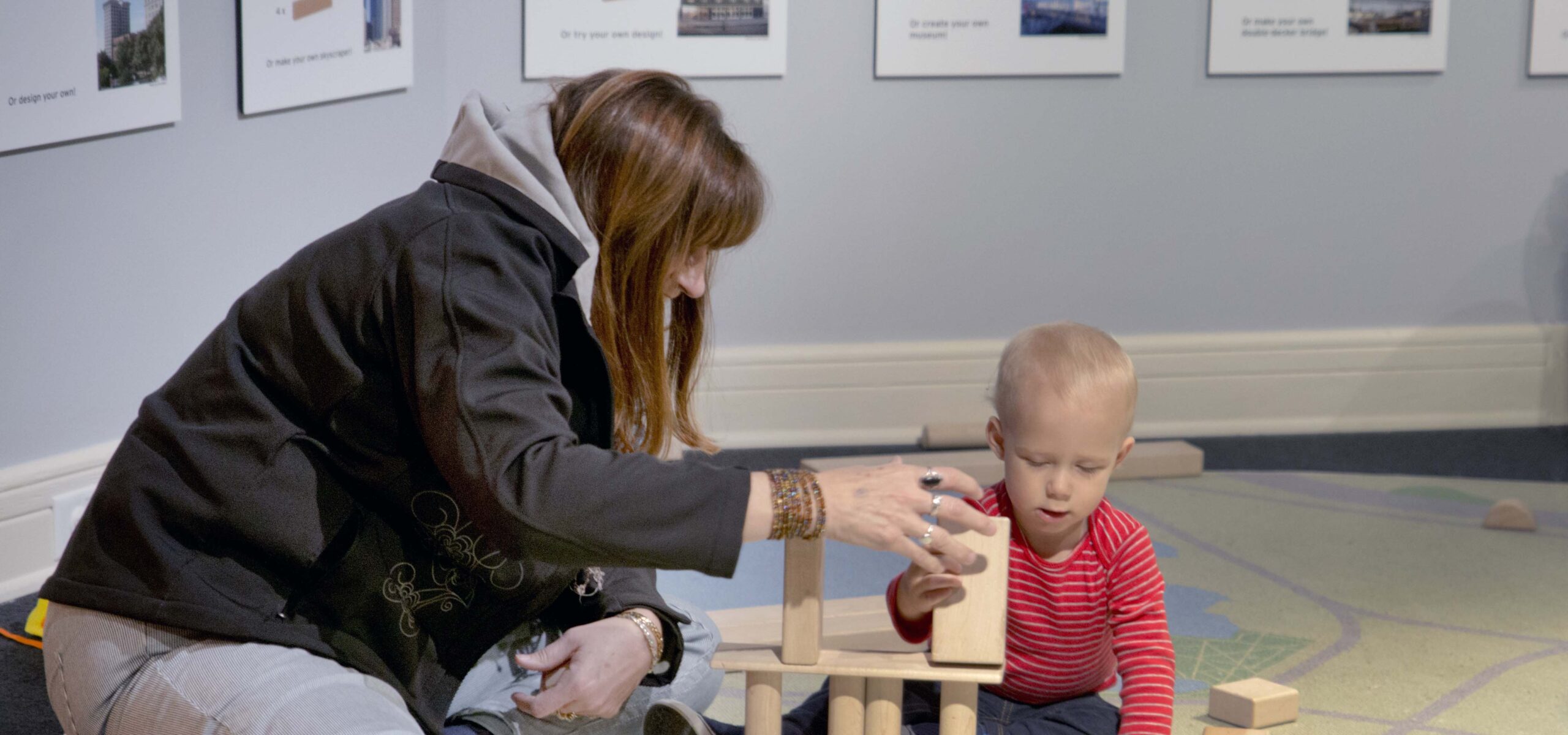 A mother playing blocks with her toddler son.