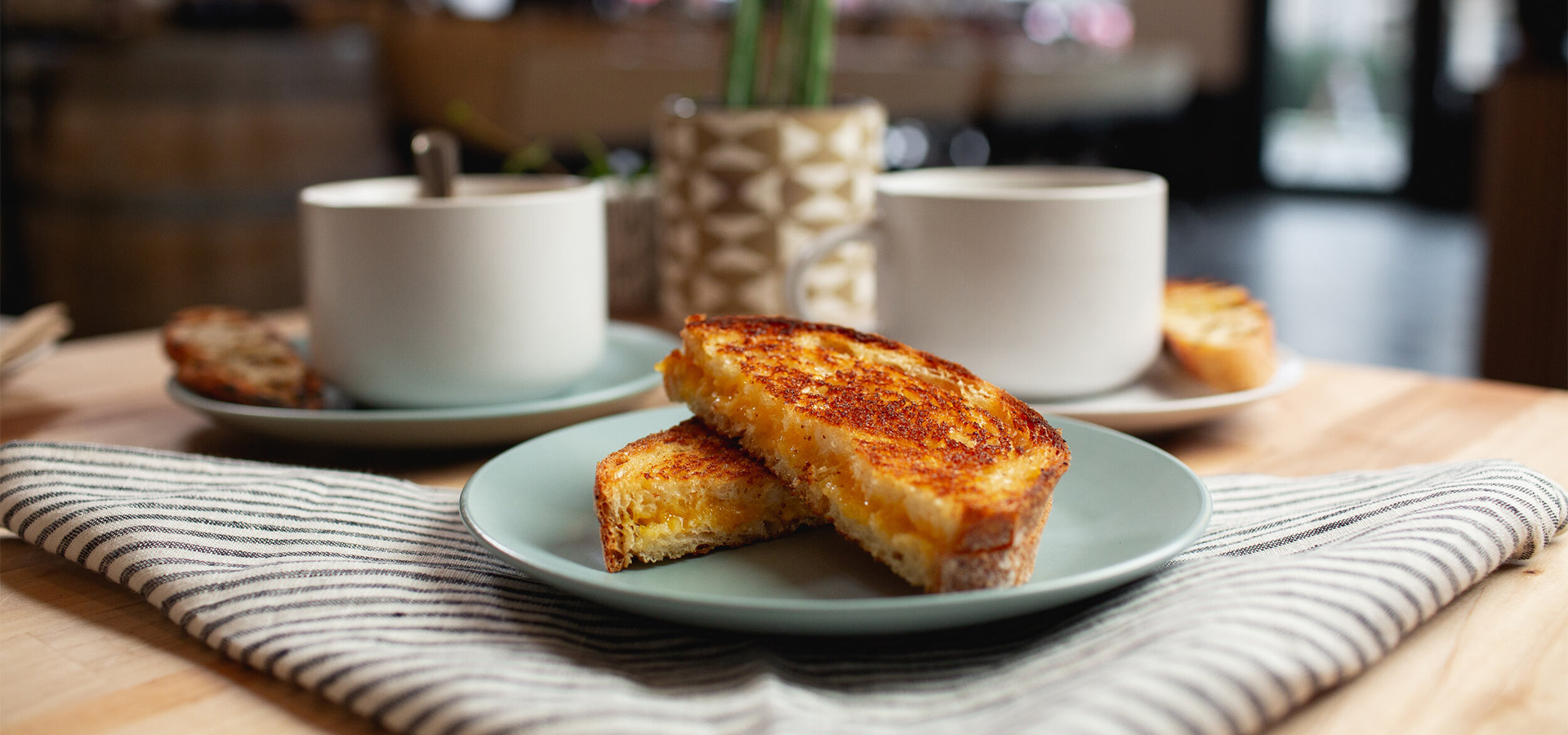 grilled cheese and two coffee mugs