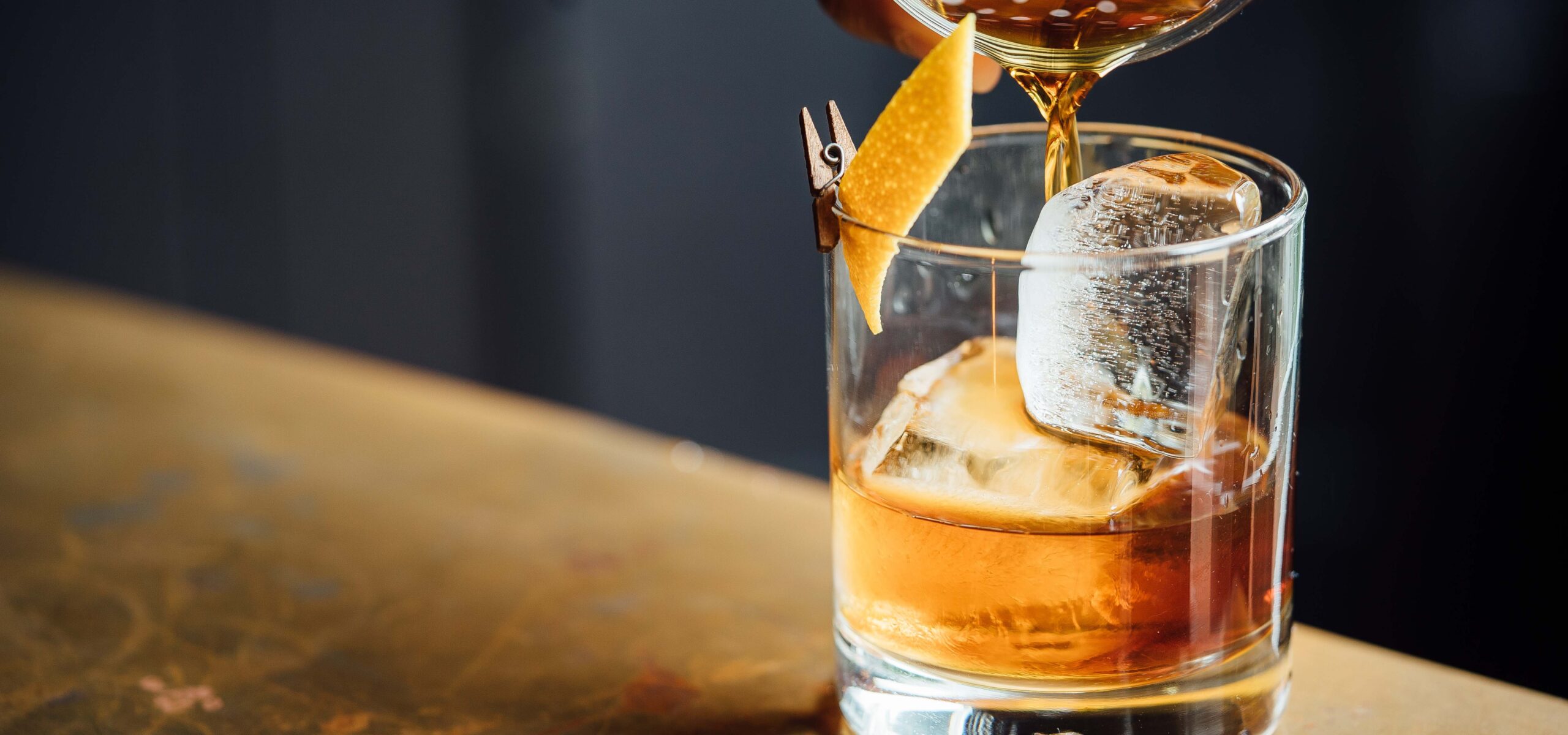 Image of a manhattan being poured into a cocktail glass.