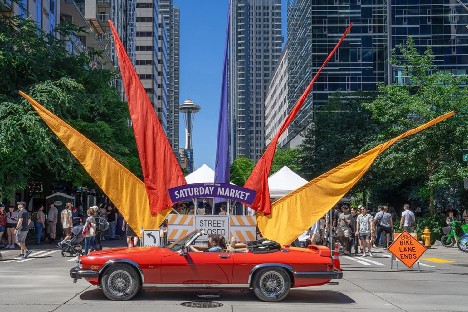 car parked in front of market sign with space needle in background