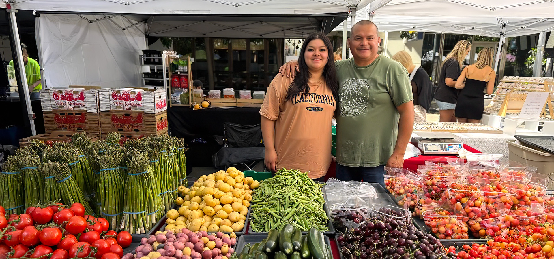 two people at farmers market veggie stand