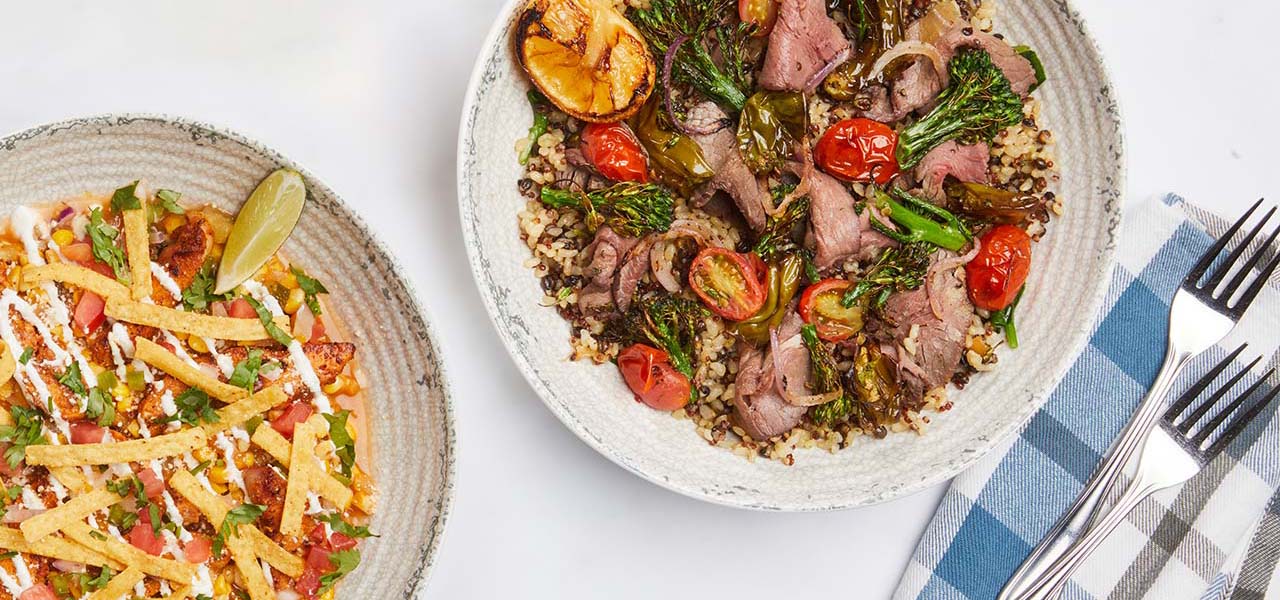 Bowls of food like steak grain salad and corn salad.