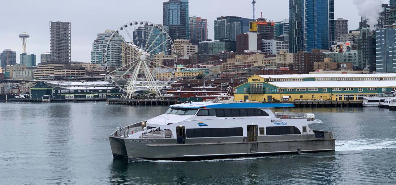 A ferry heading out with a city skyline in the background.