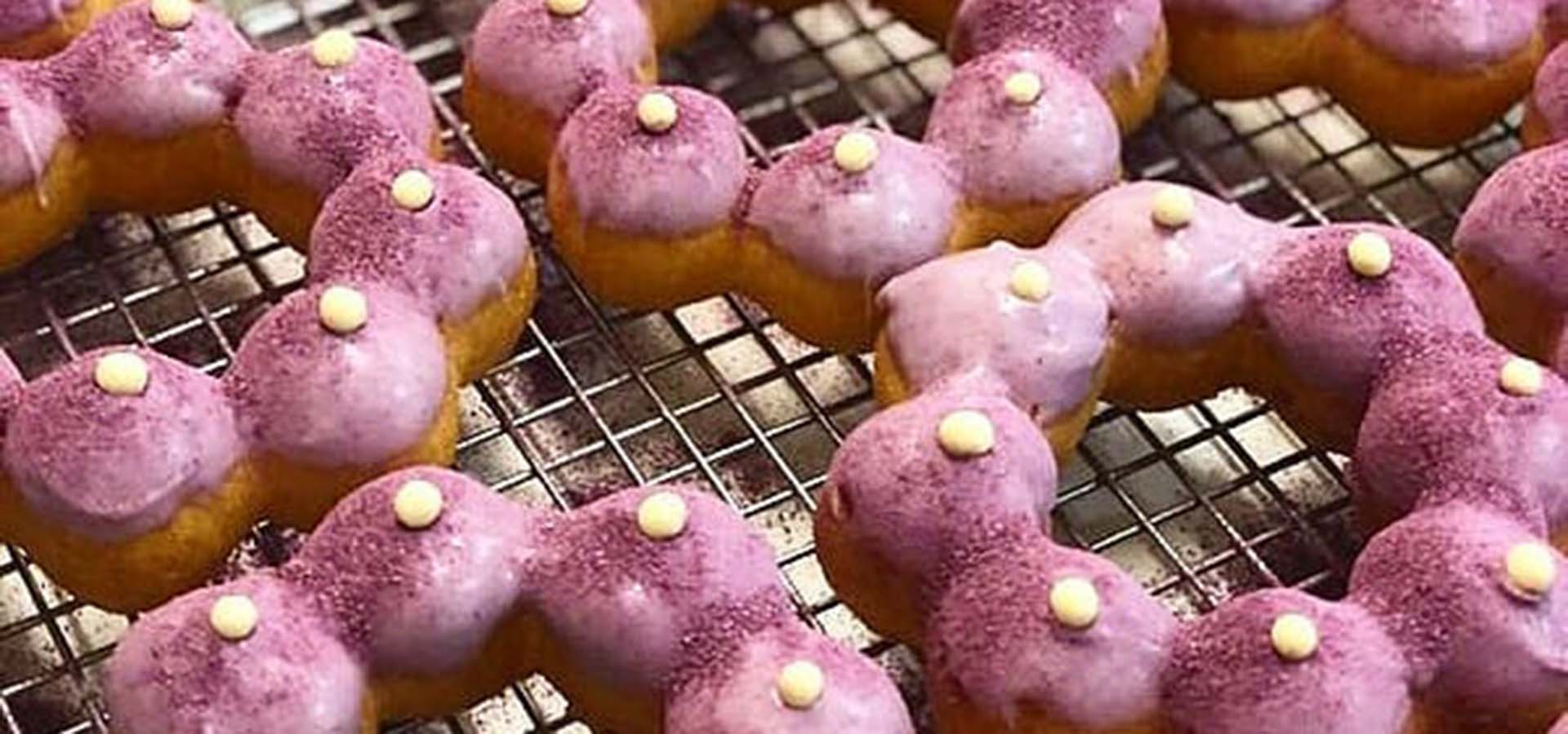 Mochi donuts with a pink glaze on a baking rack.