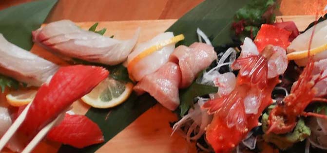 Wood plank plated with an array of sushi offerings.