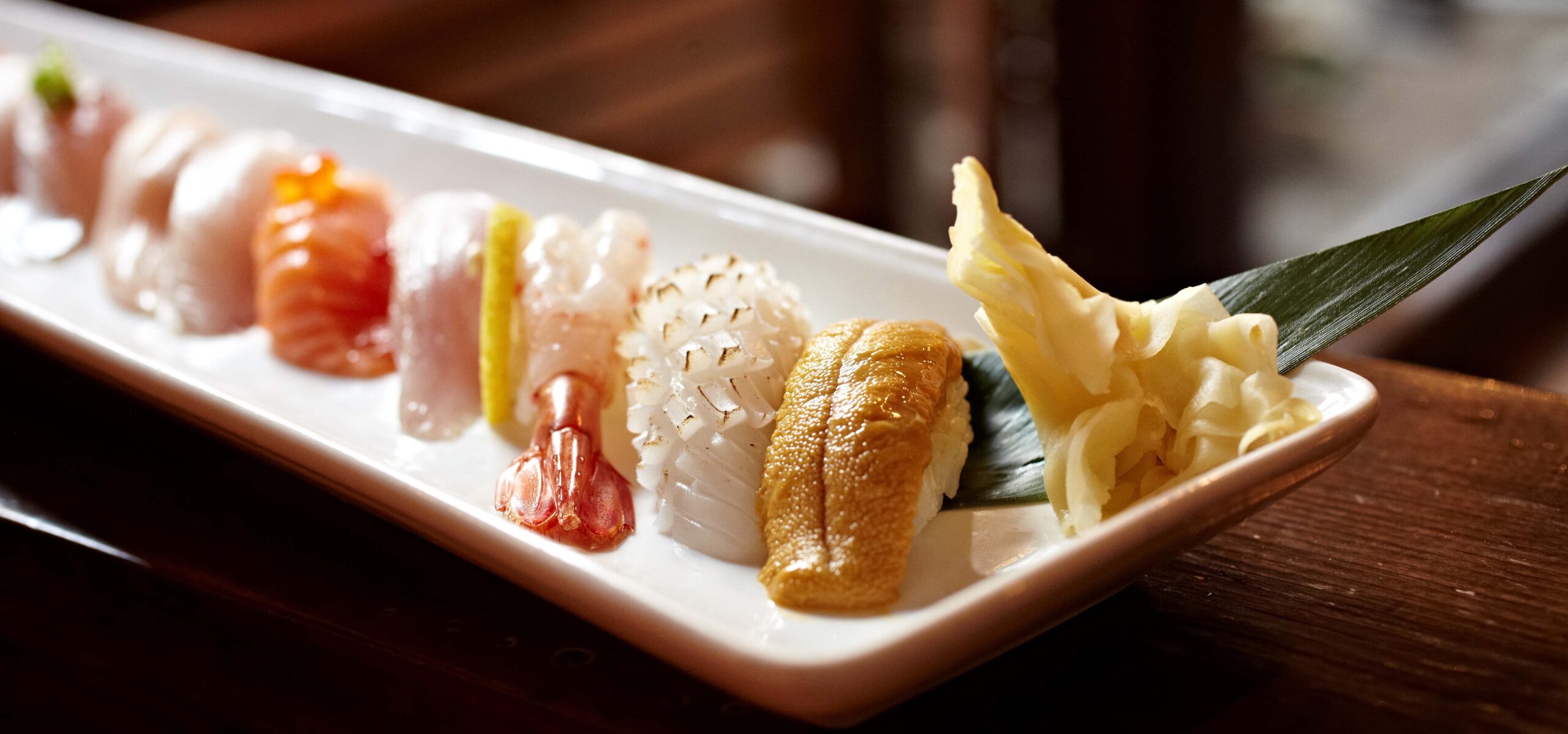 White dinner platter with a variety row of nigiri sushi.