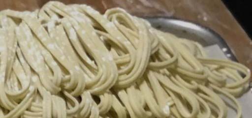 Freshly cut noodles on a metal tray.