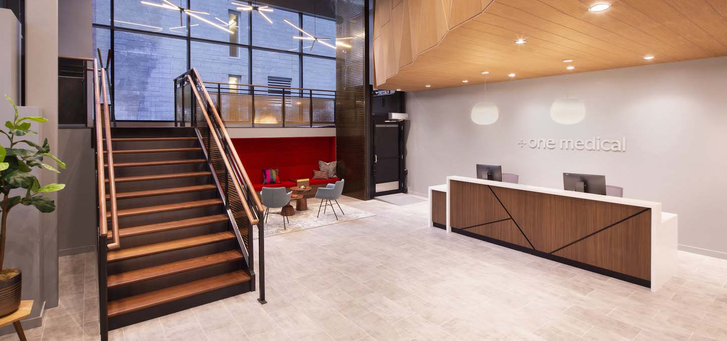 Lobby view of a medical office with front desk, stairs, and modern wood paneling.