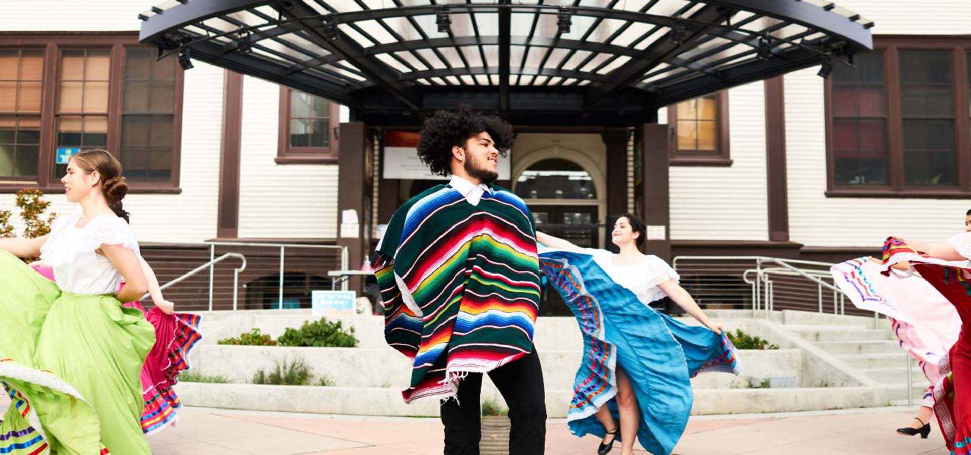 Latinx dancers in costume dancing in a plaza