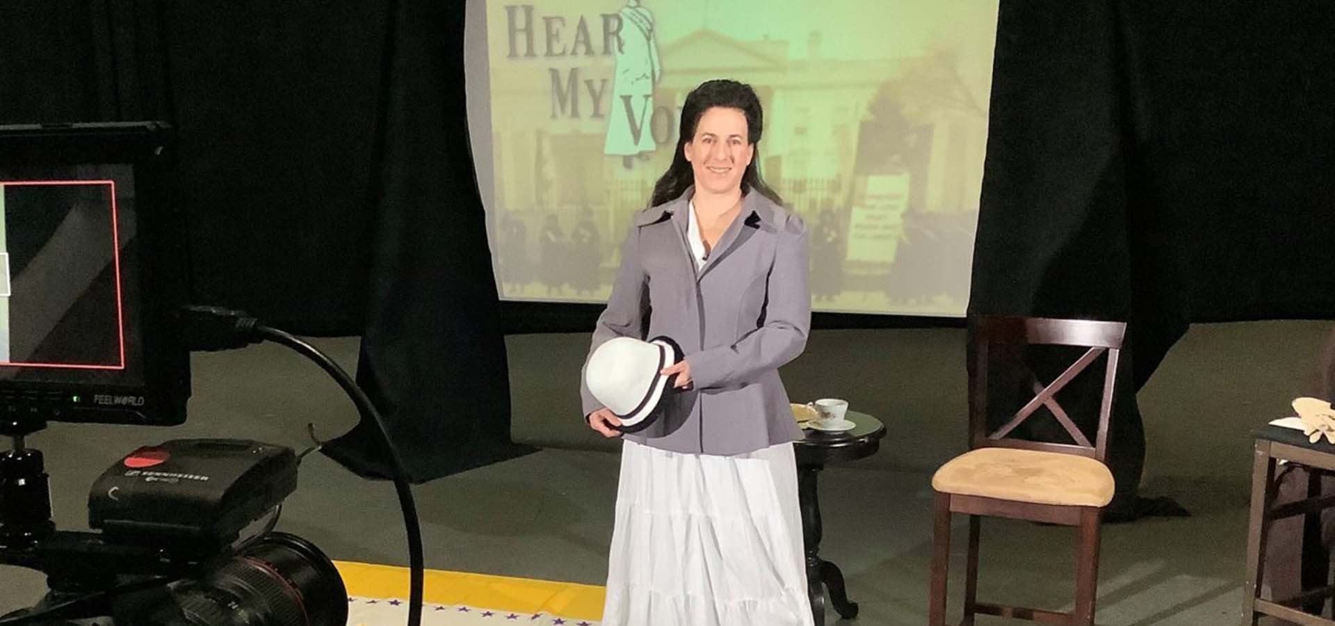 Women presenter in classroom setting holding a white hat