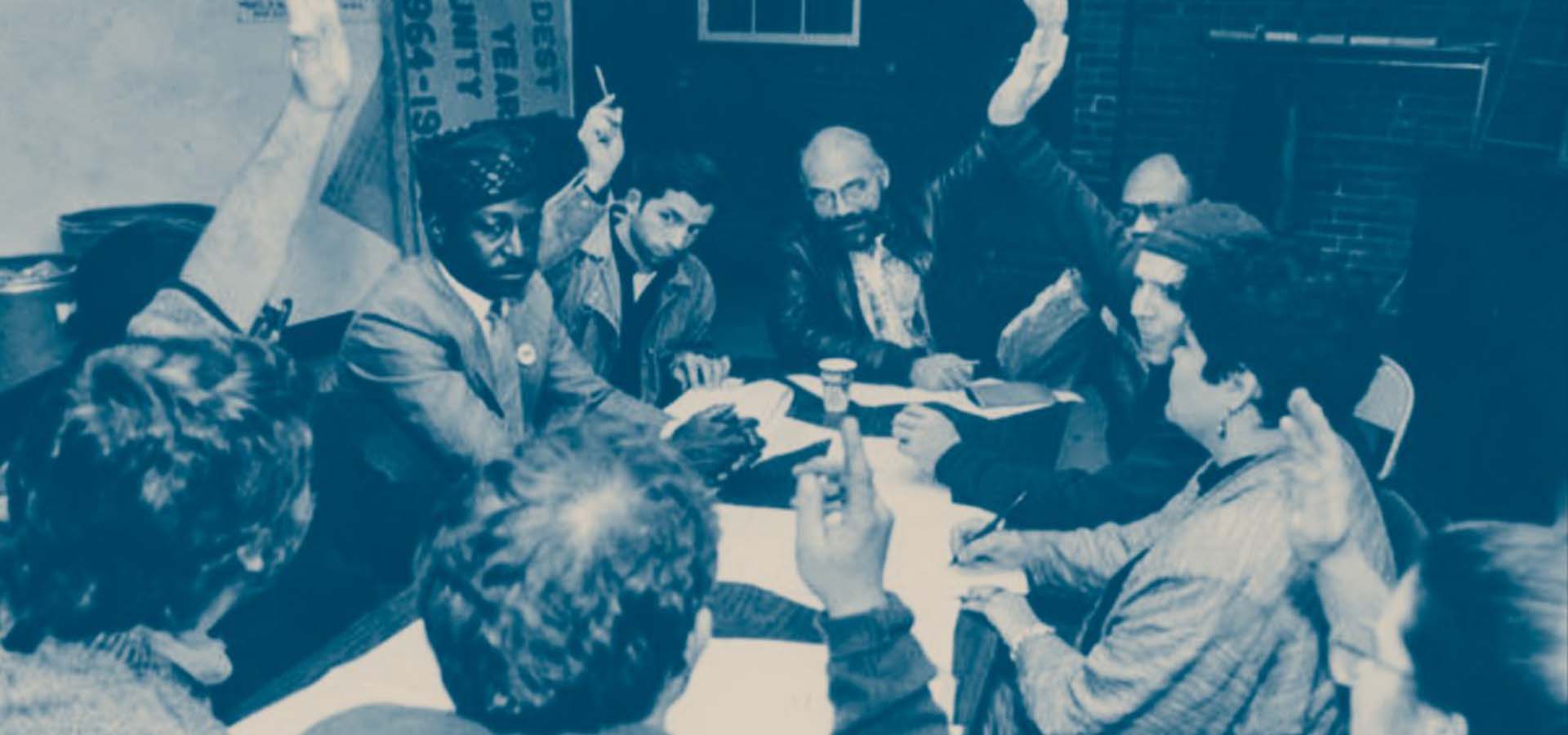 People sitting at a table voting by raising hands