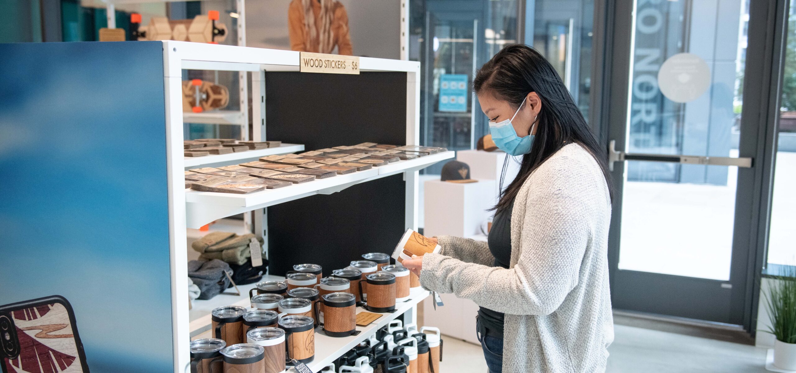 Woman looking at wooden handmade phone cases and tumblers.