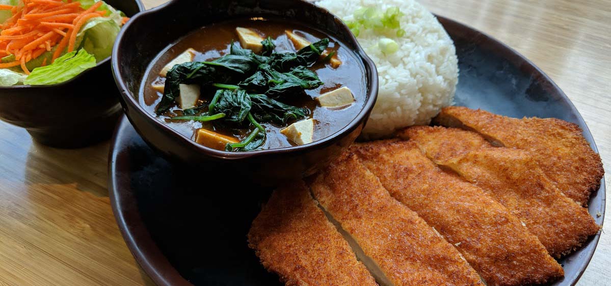 Photo of fried chicken cutlet, rice and some marinated greens.