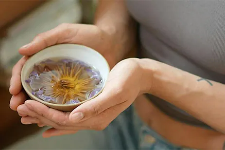 person holding glass with floating flower