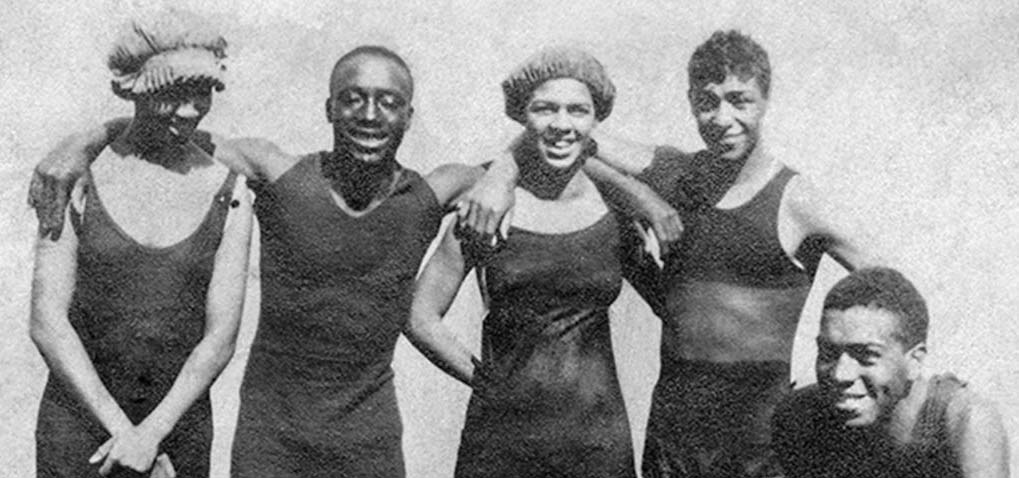 Black & white photo of people in swimsuits embracing each other.