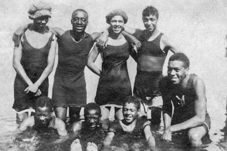 Black & white photo of people in swimsuits embracing each other.