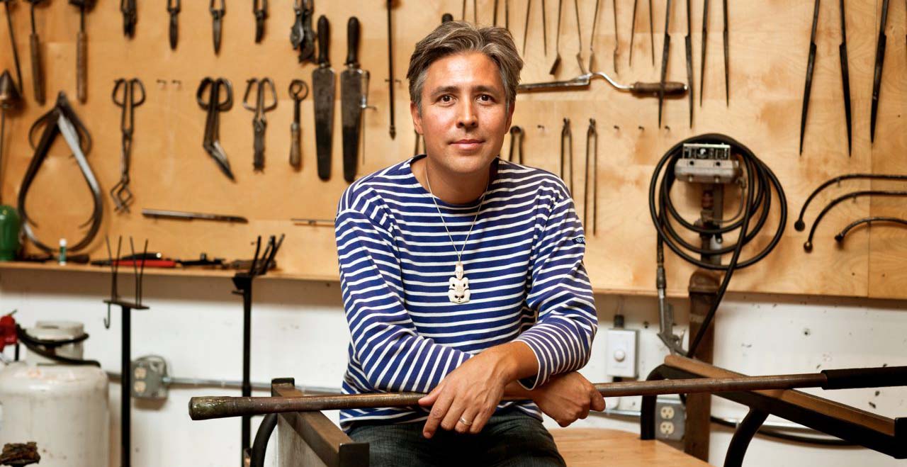 Portrait of native American artist Preston Singletary with wood-working tools hanging behind him.