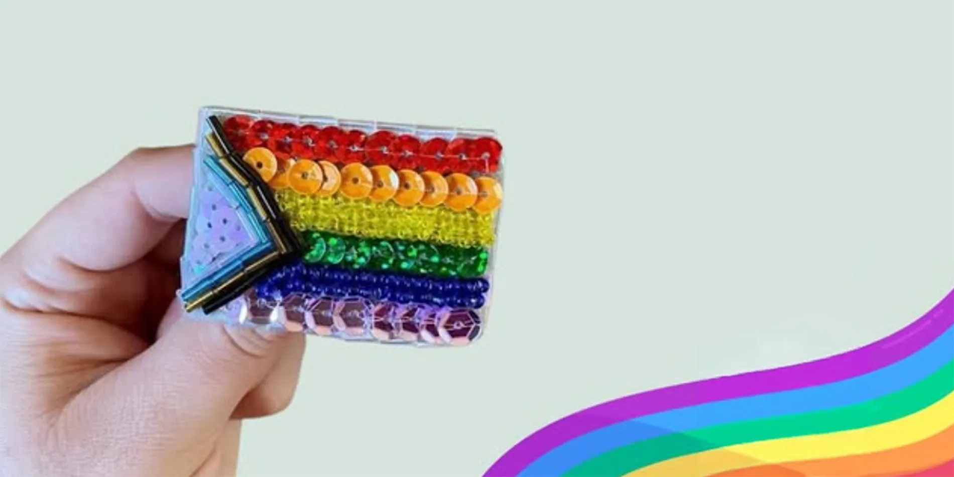 hand holding sequined pride flag pin
