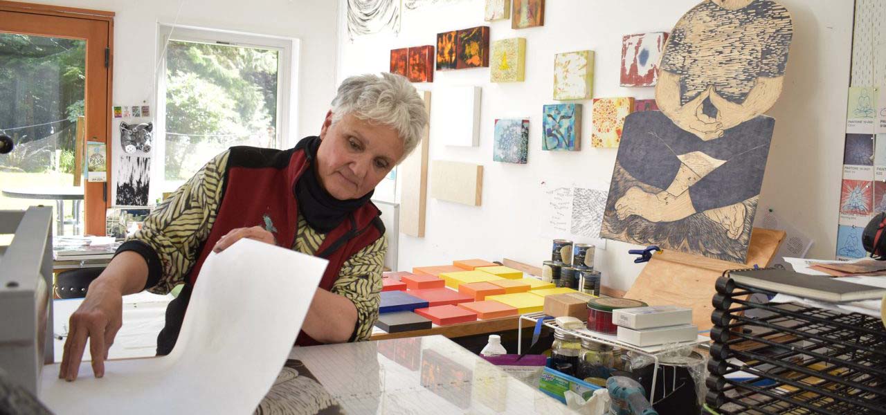 A woman printmaking in a studio.